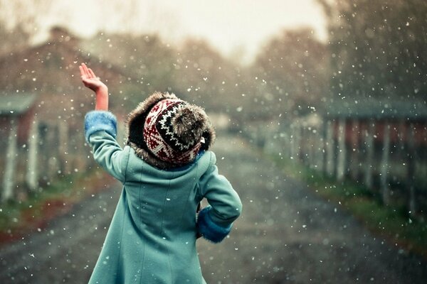 Joyful photo of a girl in a hat catching the first snowflakes