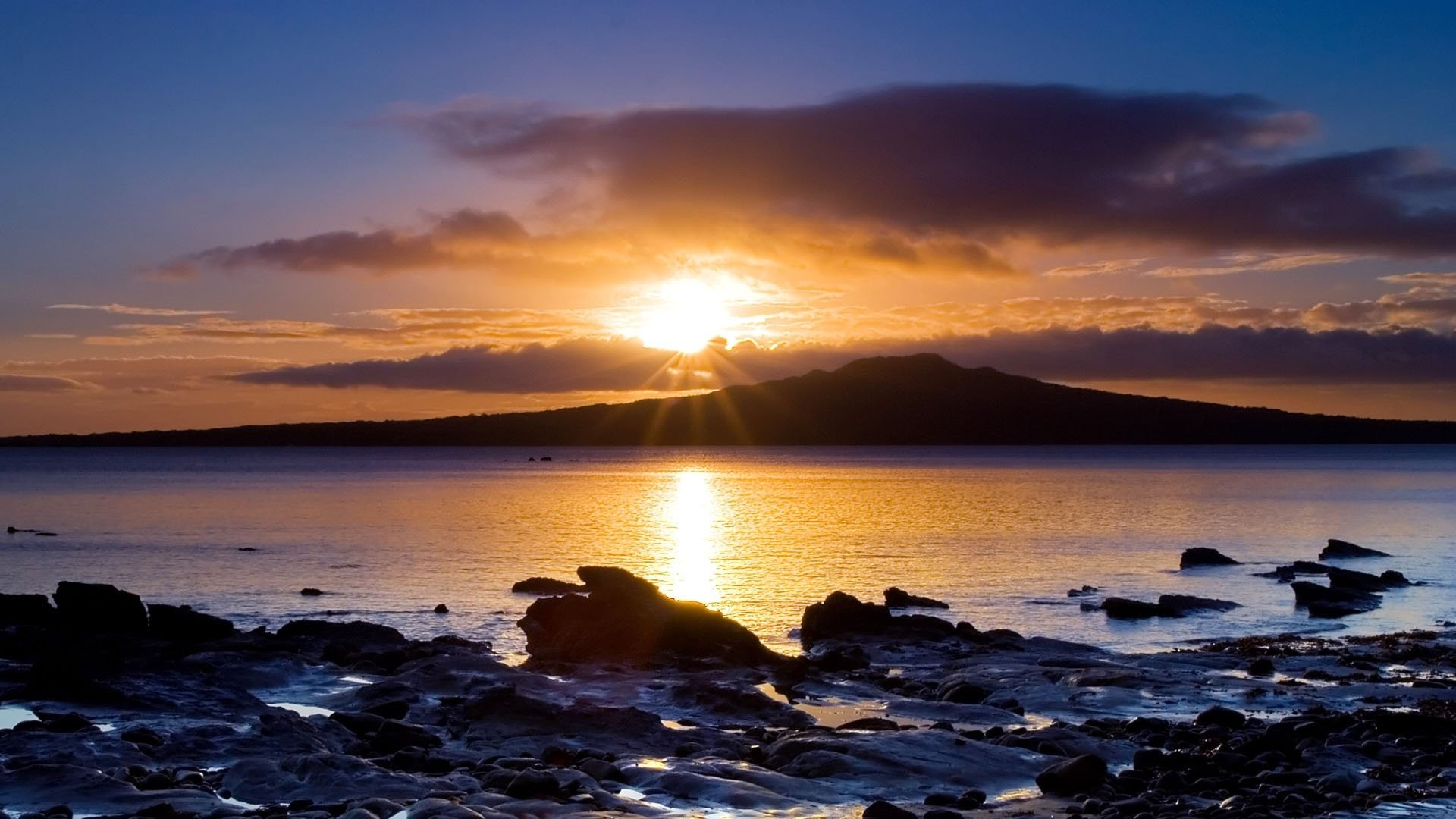 bright star the rocks near the water rays sunset water