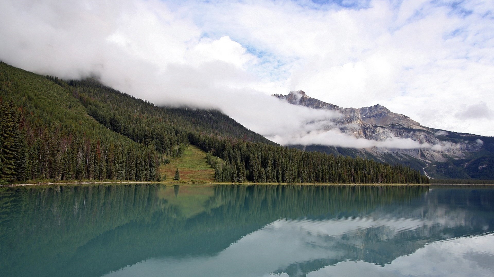 fog in the mountains a forest of spruce the slopes of the mountains gray mountain mountains water lake the sky clouds landscape view nature surface trees ate forest shore turquoise