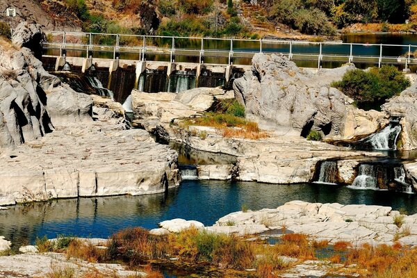 Damm am Fluss, weiße Steine mit Wasserfall