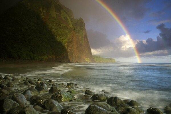 Arco iris que se va en el surf del mar