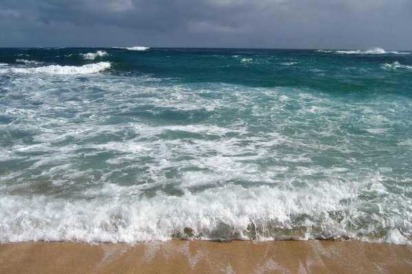 Onda imminente sulla spiaggia di sabbia