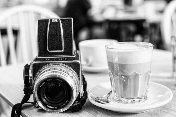 Macchina fotografica sul tavolo con piattino e bicchiere