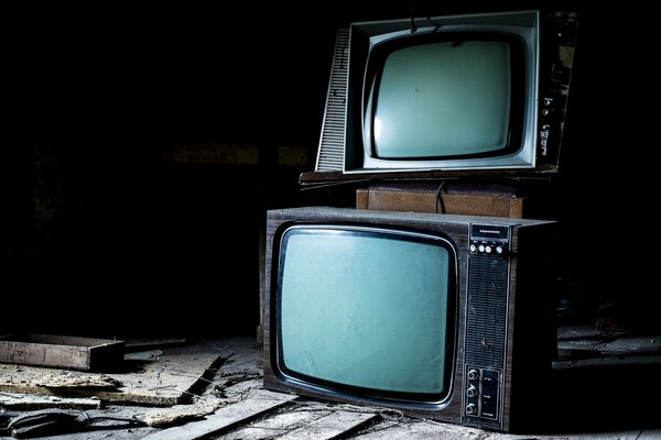 There are old televisions on top of each other on the floor