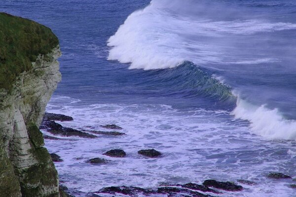 Una ola de espuma en una tormenta golpea las rocas de la naturaleza