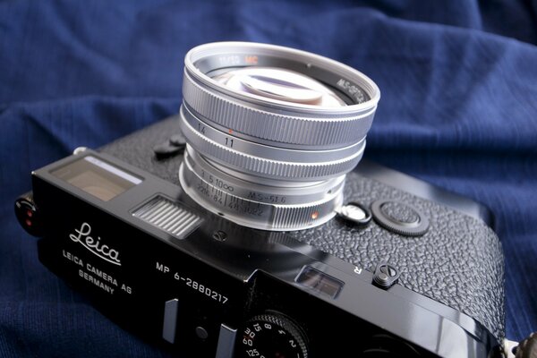 Black leica camera on a blue fabric background