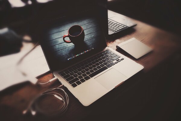 Portátil con auriculares en la mesa con la imagen en la pantalla de la taza