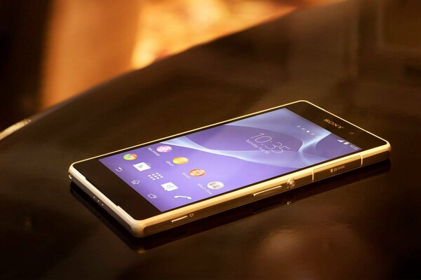 The Sony smartphone is lying on a shiny black table