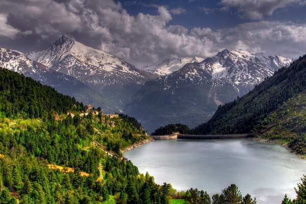 Tranquilo lago forestal y montañas en las nubes