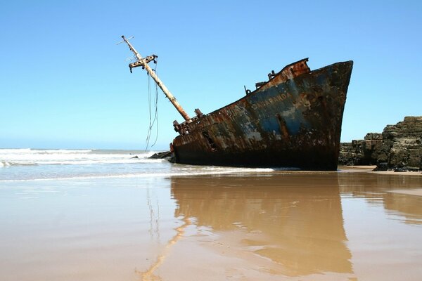 A boat in the sand against a background of clear sky and water