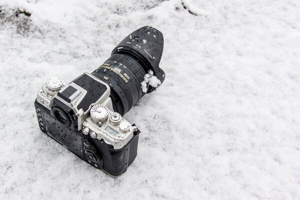 Cámara con lente grande tumbado en la nieve