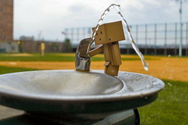 Un homme en boîte boit de l eau d une fontaine