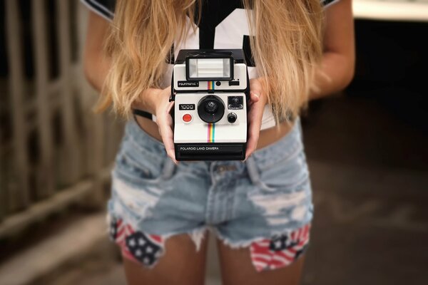 The girl holds a Polaroid camera in her hands