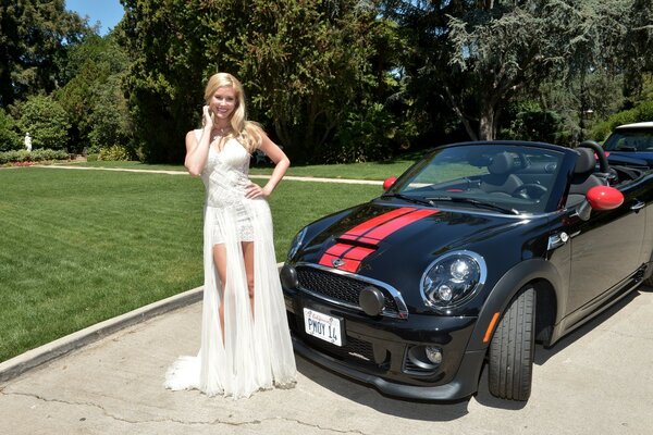 Blonde in a white dress on the background of a car