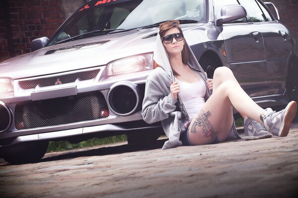 Beautiful girl with a tattoo on the background of a car