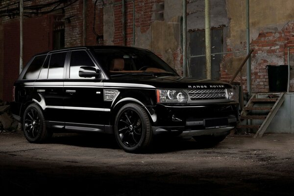 Un SUV land rover noir près d un bâtiment délabré