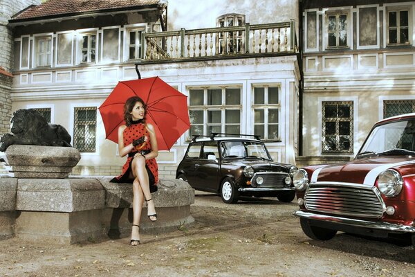Brunette avec parapluie en robe rouge et voitures rétro