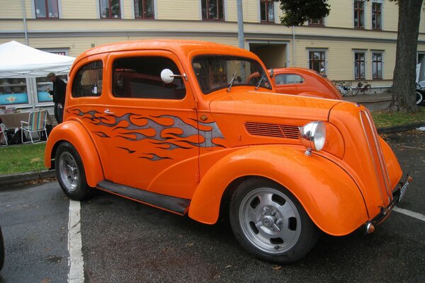Ярко-оранжевый старинный автомобиль на парковке