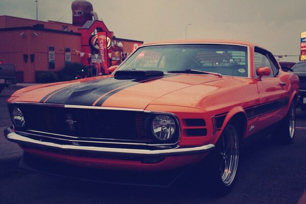 Red ford mustang on the background of signage