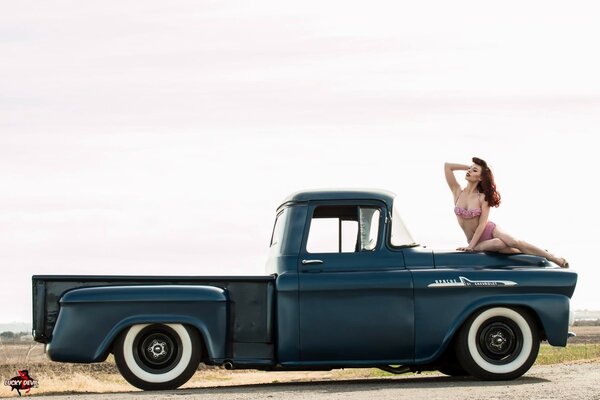 Chica sexy en el capó de un coche Vintage