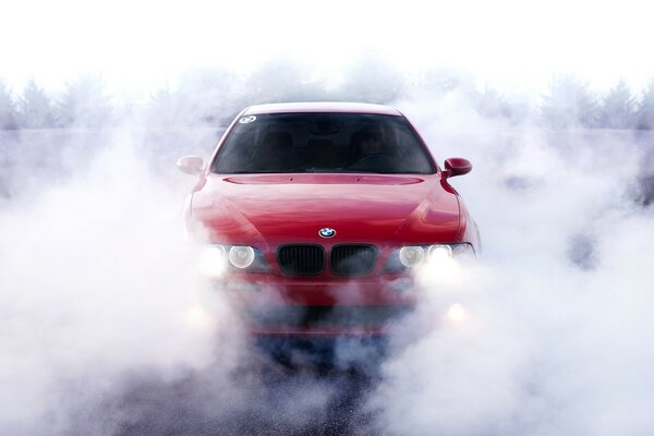 Coche rojo con los faros encendidos en el humo