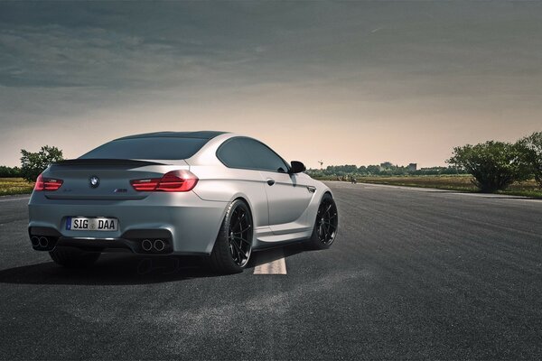 A grey bmw on a road stretching into the distance