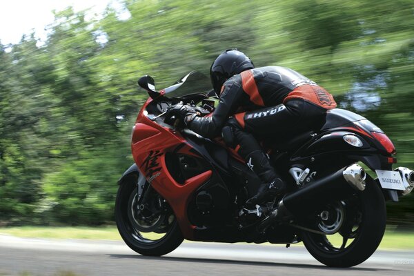 Sportmotorrad mit Fahrer bei Geschwindigkeit auf Waldhintergrund