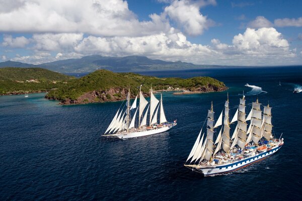 Two sailboats pass by the shore