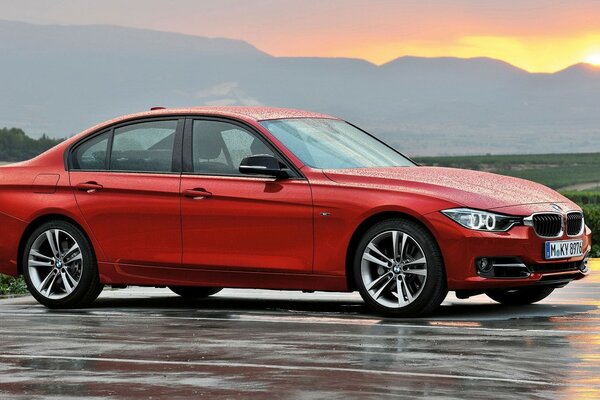 Bmw rojo, sedán en asfalto mojado