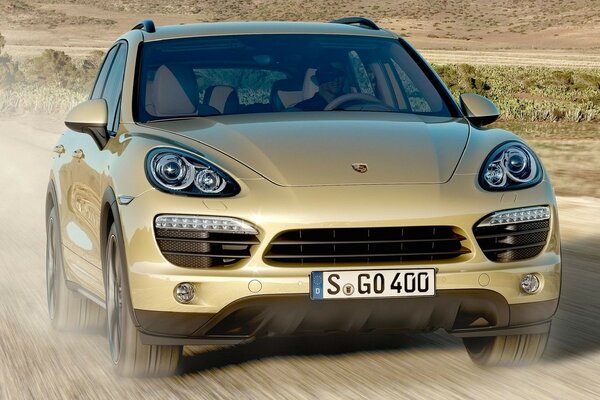 A grey Porsche rushes along a dusty road