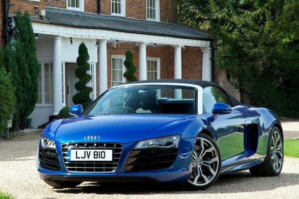 Blue Audi R8 Spyder on the background of the courtyard of the house