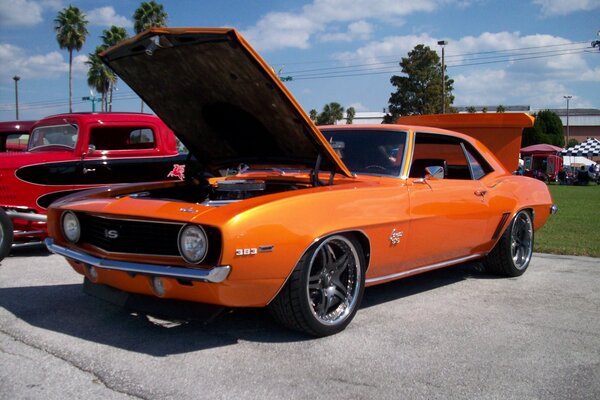 Voiture classique orange avec capot ouvert et coffre