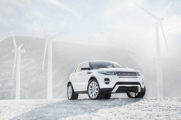 Land rover cerca de los molinos de viento en el fondo de la colina