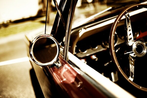 Photos of the steering wheel and rear-view mirror of a classic car