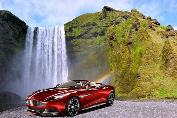 There was a red aston martin at a beautiful waterfall