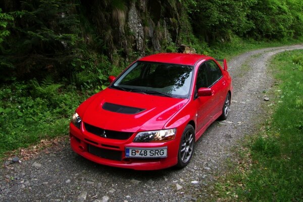 El coche rojo está parado en una carretera estrecha