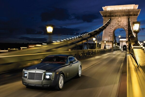 Rolls Royce grigio opaco che corre sul ponte la sera