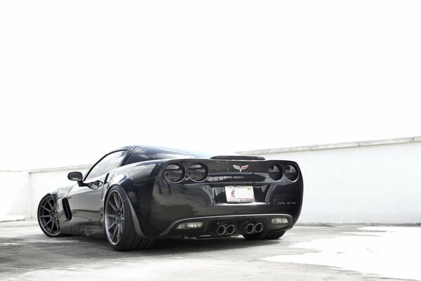 Voiture noire Chevrolet corvette sur fond de murs blancs