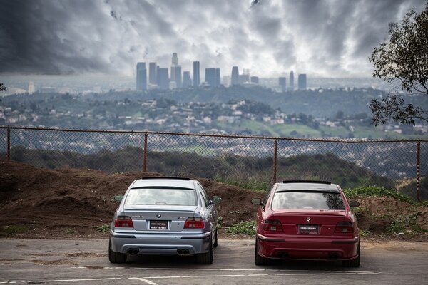 Rojo y azul bmw detrás de la valla en el fondo de la ciudad