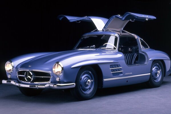 Coche clásico azul de Mercedes con las puertas arriba