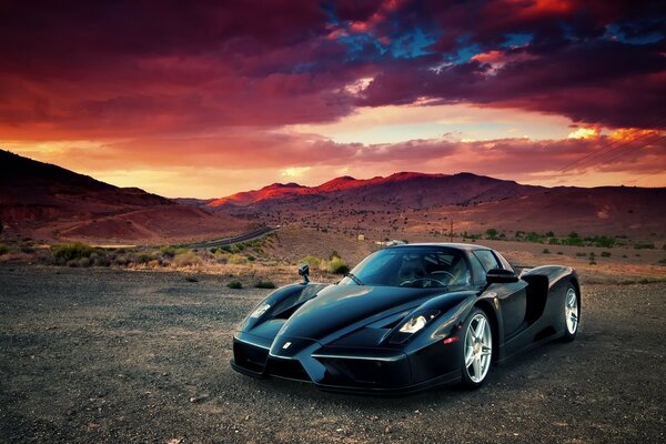 Coche negro contra las montañas y el cielo oscuro