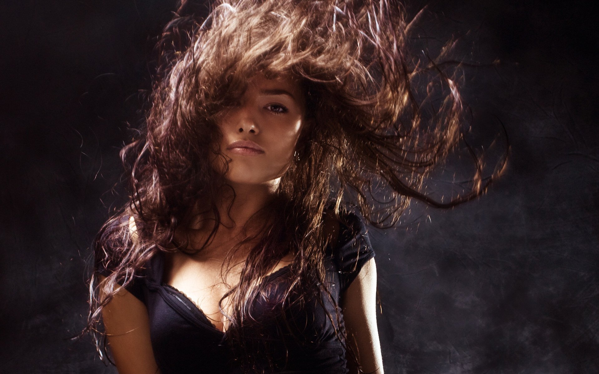 a thoughtful person girl disheveled hair the dark background brown hair face look the wind