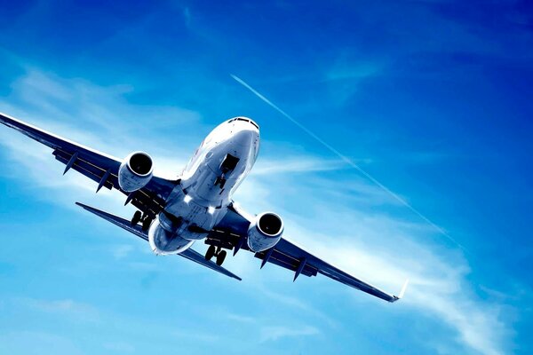 A twin-engine airplane flies through the blue sky