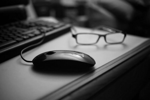 Gafas y ratón del teclado de la computadora en el Escritorio