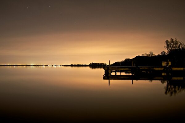 The lights of the night city are reflected in the lake