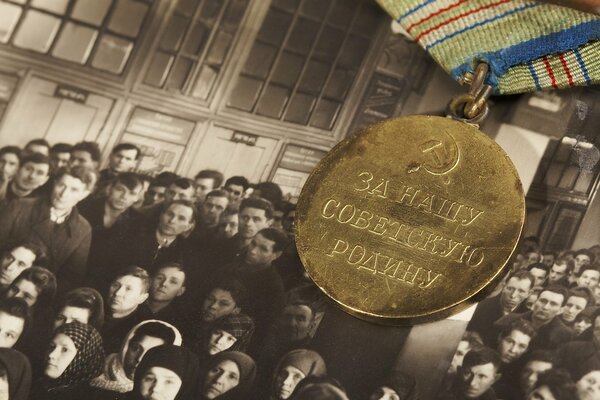 Medaglia per la nostra patria Sovietica sullo sfondo di una vecchia foto di persone