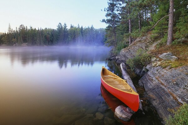 In the morning fog there is a boat by the sea