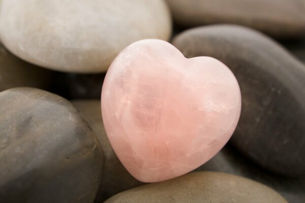 Corazón de piedra de color rosa entre las piedras comunes