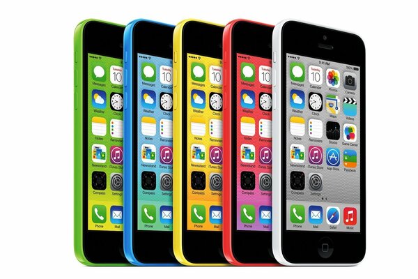 Five iPhones of different colors on a light background