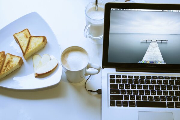 Arbeiten am Laptop bei einer Tasse Cappuccino und einem Dessert